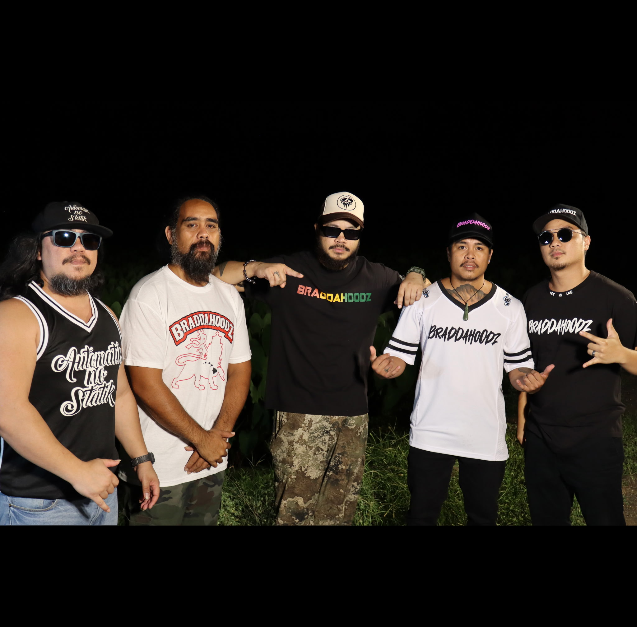 Five Braddahoodz band members standing together outdoors at night.