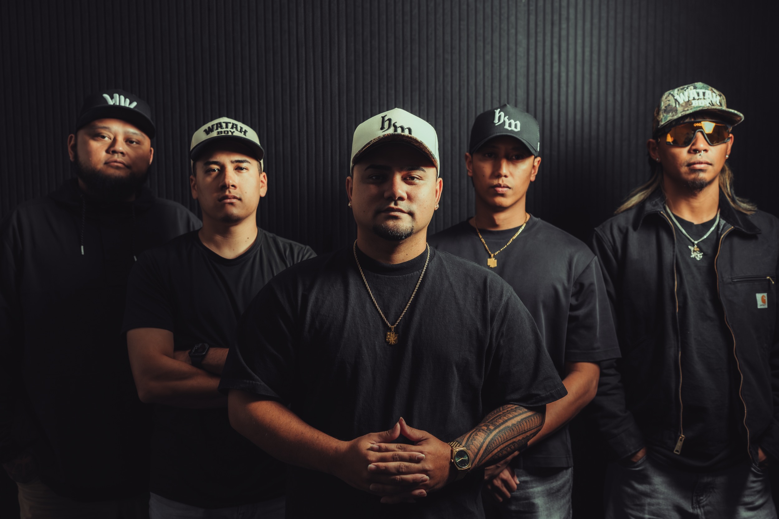 Five High Watah band members posing against a dark studio backdrop.