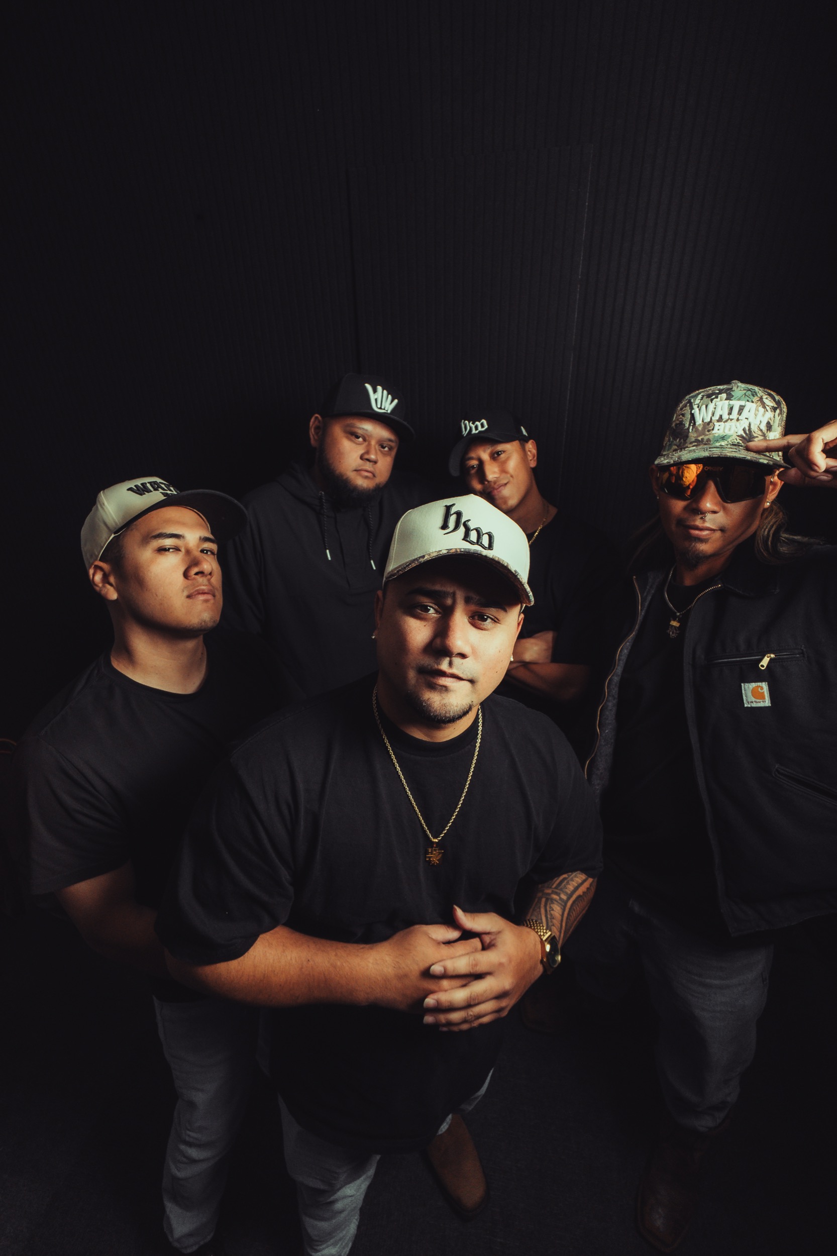 Five High Watah band members arranged together against a dark studio backdrop.